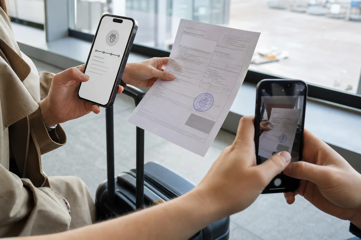 空港で税関承認済みのVAT書類を撮影し返金状況をスマートフォンで追跡する様子